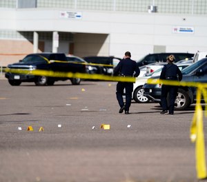 Evidence markers dot the parking lot of Hinkley High School in Aurora, Colo., on Friday, Nov. 19, 2021 after three people were shot, police said.