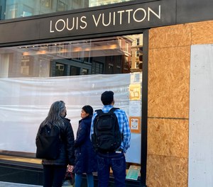 Union Square visitors look at damage to the Louis Vuitton store on Nov. 21, 2021, after looters ransacked businesses in San Francisco.
