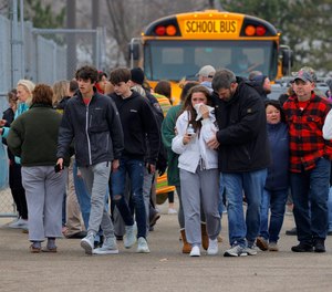 Parents walk away with their kids following a mass shooting at Oxford High School, Tuesday, Nov. 30, 2021, in Oxford, Mich.