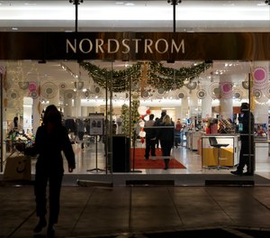 A security guard, right, stands at the entrance to a Nordstrom department store at the Grove mall in Los Angeles, Thursday, Dec. 2, 2021, where a recent smash-and-grab robbery took place.