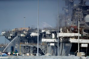 In this July 12, 2020 file photo, fire crews in San Diego spray water from the dock onto the side of the USS Bonhomme Richard.