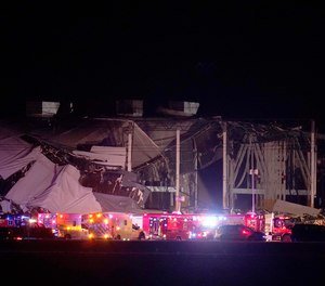 Emergency vehicles stage outside an Amazon fulfillment center after it was heavily damaged when a strong thunderstorm moved through the area Friday, Dec. 10, 2021, in Edwardsville, Ill.