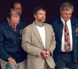 Theodore Kaczynski looks around as U.S. Marshals prepare to take him down the steps at the federal courthouse to a waiting vehicle on June 21, 1996, in Helena, Mont.