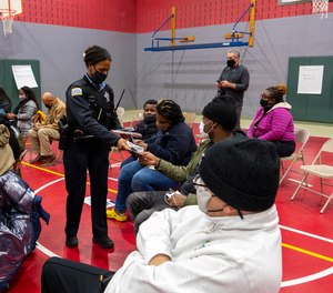 A Chicago police officer hands out informational pamphlets on how to anonymously give information to police that could help in solving crimes, during a town hall meeting at Lavizzo Elementary School on Monday, Nov. 29, 2021, in Chicago, after recent violence in the Roseland neighborhood that left an 8th grader and his mother dead in two separate shooting incidents.