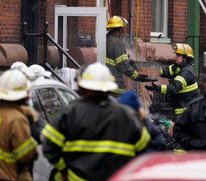 Philadelphia firefighters clear debris from the scene of a deadly row house fire, Wednesday, Jan. 5, 2022, in the Fairmount neighborhood of Philadelphia.