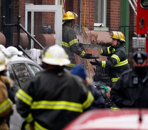 Philadelphia firefighters clear debris from the scene of a deadly row house fire, Wednesday, Jan. 5, 2022, in the Fairmount neighborhood of Philadelphia.