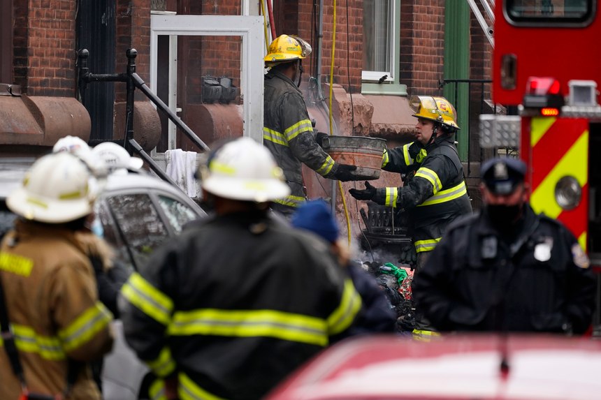 Philadelphia firefighters clear debris from the scene of a deadly row house fire, Wednesday, Jan. 5, 2022, in the Fairmount neighborhood of Philadelphia. Officials say firefighters and police responded to the fire at a three-story rowhouse early Wednesday around 6:40 a.m. and found flames coming from the second-floor windows. 