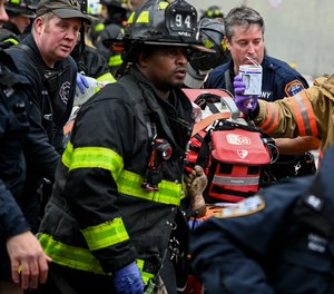 Emergency personnel bring a fire victim to an ambulance during a high rise fire on East 181 Street, Sunday, Jan. 9, 2022, in the Bronx borough of New York.
