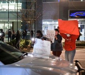Demonstrators hold up signs at a police car after a Fayetteville City Council meeting late Monday, Jan. 10, 2022, in Fayetteville, N.C.
