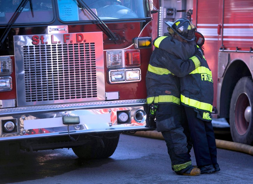 St. Louis city firefighters console one another after one of their own died in the collapse.