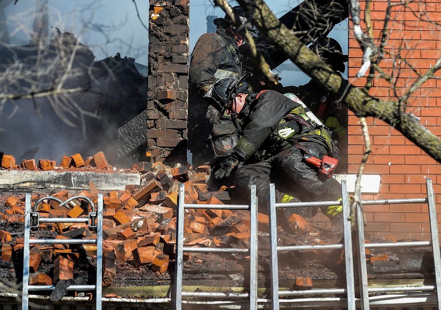 A firefighter reacts after a pile of bricks falls on him from a window eve as crews work to extinguish the fire in the structure near the corner of Hodiamont Avenue and Cote Brilliante Avenue in St. Louis, Mo., on Thursday, Jan. 13, 2022.