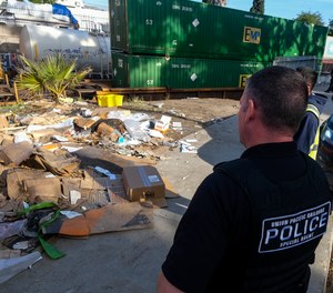 A police officer looks at shredded boxes and packages at a section of the Union Pacific train tracks in downtown Los Angeles Friday, Jan. 14, 2022.