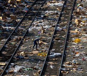 A member of the press picks up a shredded box at a section of the Union Pacific train tracks in downtown Los Angeles, Friday, Jan. 14, 2022.