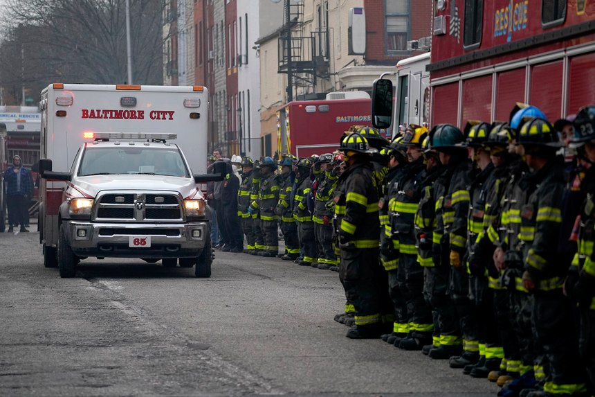 Firefighters salute as an ambulance carries a deceased firefighter after they were pulled out of a collapsed building while battling a two-alarm fire at a vacant row home, Monday, Jan. 24, 2022, in Baltimore. Officials said several firefighters died during the blaze. 