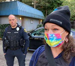 Lynnwood police Officer Denis Molloy, left, stands with Heather Turner, right, a mental health clinician from the behavioral health nonprofit Compass Health, outside a hygiene center for people experiencing homelessness, Wednesday, Nov. 17, 2021, in Lynnwood, Wash.