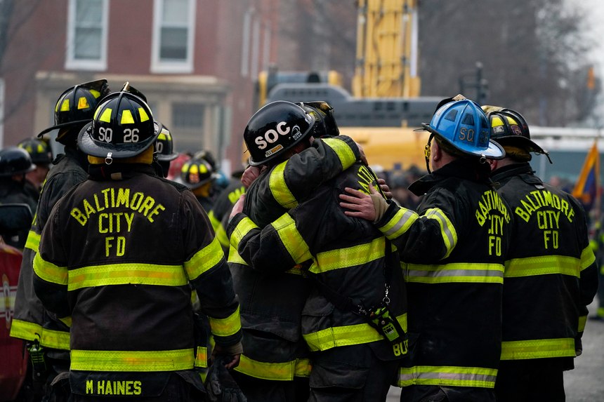 Firefighters embrace each other after a deceased firefighter was pulled out of a building collapse while battling a two-alarm fire in a vacant row home, Monday, Jan. 24, 2022, in Baltimore. Officials said several firefighters died during the blaze. The U.S. Census estimates there are 17 million vacant homes across the U.S. 