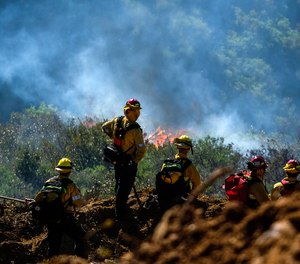 Firefighters watch as a wildfire burns Thursday, Feb. 10, 2022, in Laguna Beach, Calif. A wildfire fanned by gusty Santa Ana winds erupted in hills on the Southern California coast early Thursday but firefighters kept flames from damaging homes and after several hours officials were optimistic the blaze could be stopped.