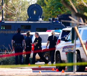 A large police presence is seen near a house where several police officers were shot after responding to a shooting inside the home Friday, Feb. 11, 2022, in Phoenix. The shooting suspect, identified by police as 36-year-old Morris Jones, was found dead in the home following a barricade situation, and a woman at the home also died later on at a local hospital.