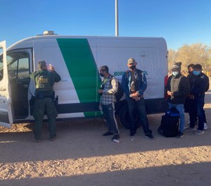 A Border Patrol agent fills out paperwork for migrants who surrendered in Yuma, Ariz., Feb. 5, 2022, after crossing the border illegally from Los Algodones, Mexico.