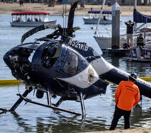 A Huntington Beach Police helicopter is lifted out of the water in Newport Beach, Calif., Sunday, Feb. 20, 2022. A