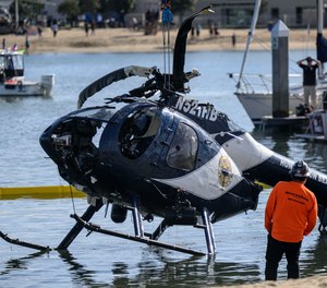 A crane is used to lift a Huntington Beach Police helicopter out of the water in Newport Beach, Calif., on Feb. 20, 2022. The crash killed 44-year-old Nicholas Vella of the Huntington Beach Police Department.