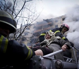 Firefighters evacuate an elderly woman from an apartment building hit by shelling in Kyiv, Ukraine, Monday, March 14, 2022.