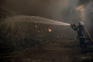 A Ukrainian firefighter hoses down a destroyed warehouse after a Russian bombardment on the outskirts of Kyiv on March 24.