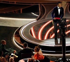 Presenter Chris Rock, right, speaks onstage as Jada Pinkett Smith and Will Smith, bottom left, look on after Smith went onstage and slapped Rock at the Oscars, Sunday, March 27, 2022, at the Dolby Theatre in Los Angeles.