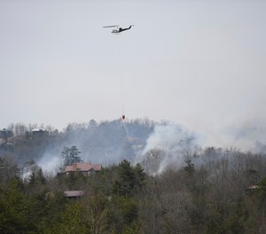 A helicopter dumps water onto a wildfire Wednesday, March 30, 2022, in Sevierville, Tenn. Firefighters sought to get a handle Wednesday on a wildfire spreading near Great Smoky Mountains National Park in Tennessee, amid mandatory evacuations as winds whipped up ahead of a line of strong storms forecast to move in overnight.