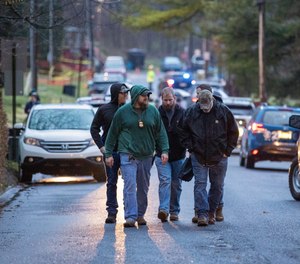 Police personnel walk in Lebanon, Pa., after a police officer was killed and two others wounded by a 34-year-old suspect, who was also shot and killed, Thursday, March 31, 2022.