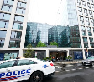A Metropolitan Police patrol car is parked in front of a a luxury apartment building in Southeast Washington, Thursday, April 7, 2022. Federal prosecutors on Wednesday charged two men they say were posing as federal agents, giving free apartments and other gifts to U.S. Secret Service agents, including one who worked on the first lady's security detail.