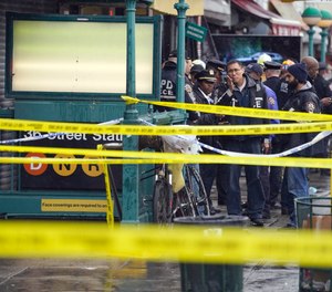 New York City Police Department personnel gather at the entrance to a subway stop in the Brooklyn borough of New York, Tuesday, April 12, 2022. 10 passengers were shot and another 13 were injured in a shooting rampage.