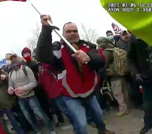 This still frame from Metropolitan Police Department body worn camera video shows Thomas Webster, in red jacket, at a barricade line at on the west front of the U.S. Capitol on Jan. 6, 2021, in Washington. Webster, a retired New York Police Department officer, was sentenced on Thursday, Sept. 1, 2022, to 10 years in prison for attacking the U.S. Capitol and using a metal flagpole to assault one of the police officers trying to hold off a mob of Donald Trump supporters. (Metropolitan Police Department via AP)