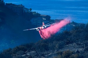 A plane drops retardant on a wildfire near homes on Feb. 10 in Laguna Beach, Calif. U.S. officials are testing a new wildfire retardant after two decades of buying millions of gallons annually from one supplier, but watchdogs say the expensive strategy is overly fixated on aerial attacks at the expense of hiring more fire-line digging ground crews.