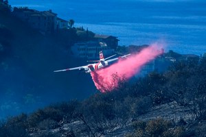 A plane drops retardant on a wildfire near homes on Feb. 10 in Laguna Beach, Calif. U.S. officials are testing a new wildfire retardant after two decades of buying millions of gallons annually from one supplier, but watchdogs say the expensive strategy is overly fixated on aerial attacks at the expense of hiring more fire-line digging ground crews.