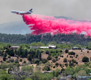 A slurry bomber dumps the fire retardant between the Calf Canyon/Hermit Peak Fire and homes on the westside of Las Vegas, N.M., Tuesday, May 3, 2022. Several types of aircraft joined the fight to keep the fire away for the Northern New Mexico town.
