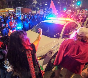 Demonstrators surround a police officer in his vehicle near Pershing Square after protesting outside the U.S. Courthouse in response to leaked draft of the Supreme Court's opinion to overturn Roe v. Wade in Los Angeles, Tuesday, May 3, 2022.