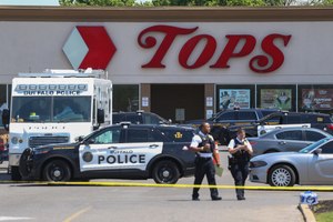 Police officers walked outside the Tops grocery store on May 15 in Buffalo, N.Y. A white 18-year-old wearing military gear and livestreaming with a helmet camera opened fire with a rifle at the supermarket, killing and wounding people.