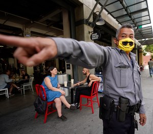 A private security guard points to the street site near Grand Central Market on Sunday, May 15, 2022, in Los Angeles. A man was fatally shot outside the popular food hall on Saturday.