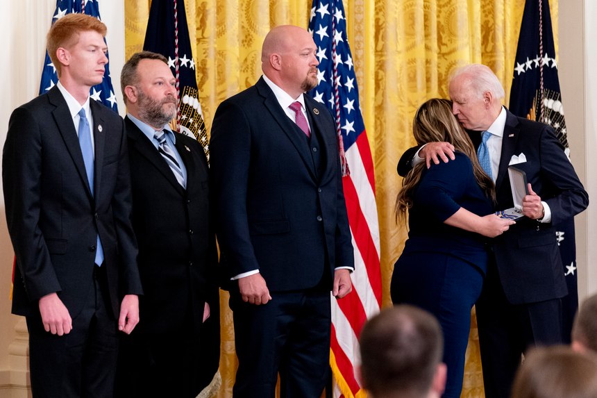 From left, Concord, N.C., Police Officers Kaleb Robinson, Paul Stackenwalt, and Kyle Baker, watch as Haylee Shuping, the wife of fallen officer Jason Shuping, hugs President Joe Biden as he awards her late husband the Public Safety Officer Medal of Valor.