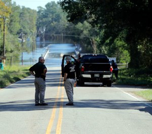 Responders congregate near where two people drowned the evening before when they were locked in a Horry County Sheriff's department transport van in Marion County, S.C. A deputy charged in the deaths ignored barricades and drove into rapidly rising floodwaters against advice from his supervisors and officials on the South Carolina highway, a prosecutor said Monday, May, 16, 2022.