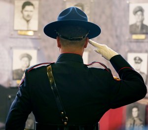 A member of the Mississippi Highway Patrol Honor Guard salutes before the mural of portraits honoring lawmen with the Mississippi Department of Public Safety who were killed in the line of duty. The memorial service is one of many held across the country during the National Police Week.