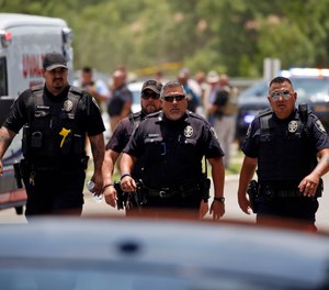 Police walk near Robb Elementary School following a shooting on May 24 in Uvalde, Texas. A gunman fatally shot 19 children and two teachers at the school. Over an hour passed from the time officers followed the 18-year-old gunman into the school and when they finally entered the fourth grade classroom where he was holed up and killed him. Meanwhile, students trapped inside repeatedly called 911 and parents outside the school begged officers to go in.