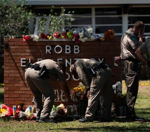 Two Texas Troopers light a candle at Robb Elementary School in Uvalde, Texas, Wednesday, May 25, 2022.