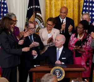 President Joe Biden hands a pen to Vice President Kamala Harris after signing the executive order in the East Room of the White House, Wednesday, May 25, 2022, in Washington.