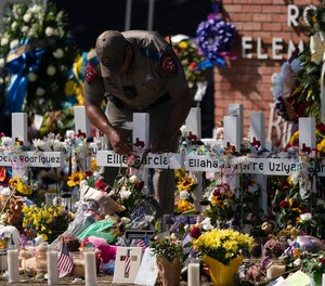 A state trooper places a tiara on a cross honoring Ellie Garcia, one of the victims killed in this week's elementary school shooting in Uvalde, Texas Saturday, May 28, 2022.
