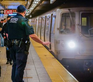 As a subway train enters the Canal St. Q and N station, a NYPD transit officer from the anti terrorism unit gestures to the driver, Tuesday, May 24, 2022, in New York.