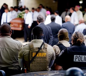 Law enforcement personnel look on as the caskets of two Uvalde shooting victims are carried by pallbearers following a joint service at Sacred Heart Catholic Church, June 1, 2022, in Uvalde, Texas.
