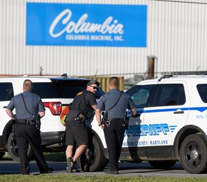 Police stand near where a man opened fire at a business, killing three people before the suspect and a state trooper were wounded in a shootout, according to authorities, in Smithsburg, Md., Thursday, June 9, 2022.