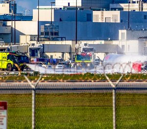Miami-Dade Fire-Rescue vehicles are seen next to a RED Air plane that caught fire after the front landing gear collapsed upon landing at Miami International Airport on Tuesday.